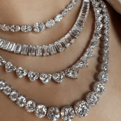 Close-up of four Equestrian Line diamond necklaces layered on a neck, each showcasing different diamond shapes—round, baguette, and heart—in white metal settings.