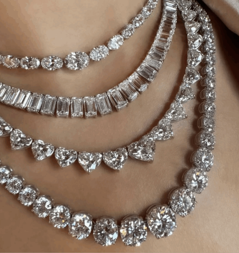 Close-up of four Equestrian Line diamond necklaces layered on a neck, each showcasing different diamond shapes—round, baguette, and heart—in white metal settings.